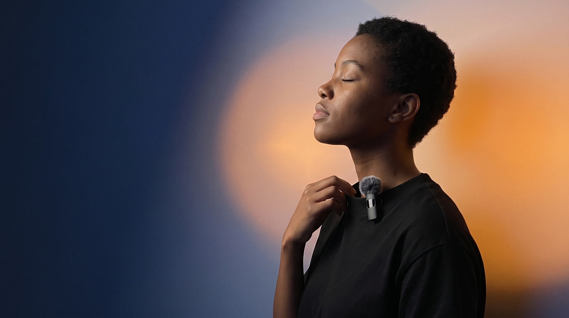 A creator wearing a Mini Mic Pro clipped to her collar, eyes closed, lit in blue and amber